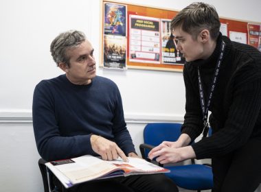 two men talking and pointing at paperwork